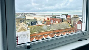 A view from a window overlooking a coastal town with buildings, a beach, and the sea. - Spacious 2 Bedroom Apartment in Margate (Margate)