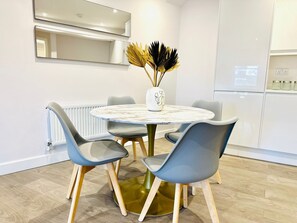 A modern dining area with a round table, four chairs, and a vase with decorative elements. - Spacious 2 Bedroom Apartment in Margate (Margate)