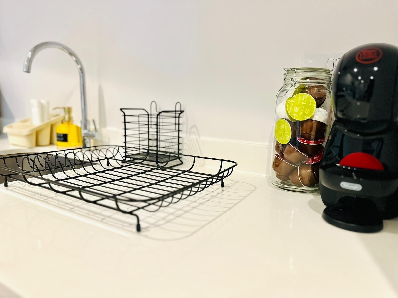 A kitchen counter with a wire rack, a jar of spices, and a coffee maker.