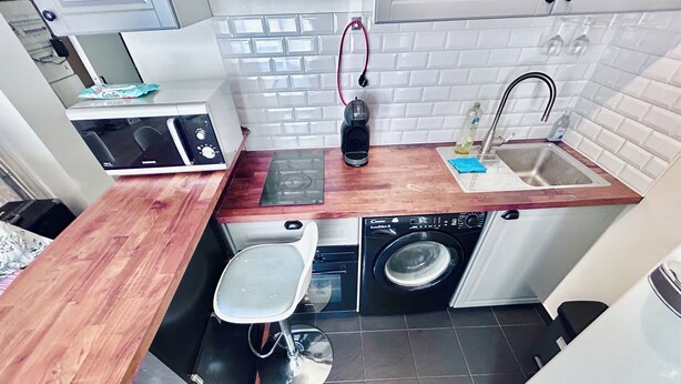 Una cocina compacta equipada con microondas, tostadora, cafetera, lavaplatos y lavadora.