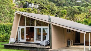 Ein modernes Haus mit großer Glasfront, einer überdachten Veranda und einer Satellitenschüssel.