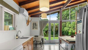 Eine moderne Küche mit Holzausstattung, einem eingebauten Backofen und einem großen Fenster mit Blick auf einen Garten.