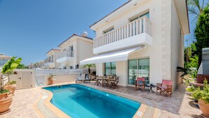 Une piscine avec des chaises longues, un espace salon extérieur et un bâtiment doté d’un balcon.