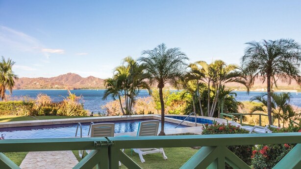 Zona de piscina con vista al océano y montañas.