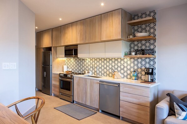 A modern kitchen with wooden cabinets, a microwave, a stove, and a coffee machine.