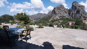 A patio with a table and chairs, a view of rocky mountains, and a clear sky.