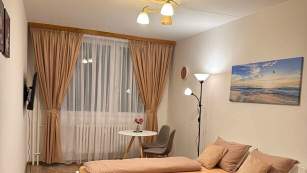 A bedroom with a bed, a chair, a table, and a painting on the wall.