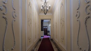 Un couloir agrémenté de décorations murales élaborées et surmonté d’un lustre.
