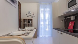 Une cuisine compacte avec un coin repas, une horloge au mur et un îlot central.
