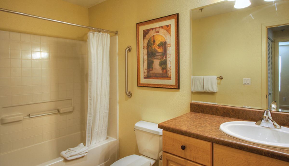 Une salle de bain équipée d’une douche, de toilettes, d’un lavabo et d’un tableau encadré au mur.