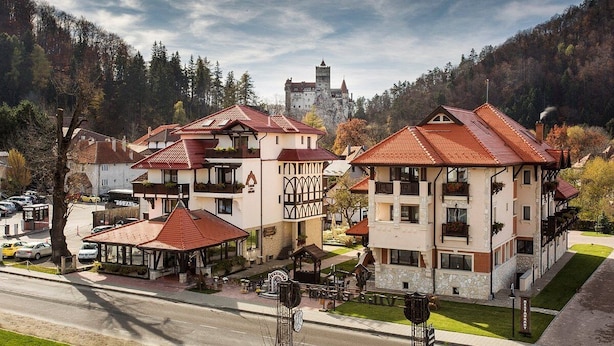 A hotel with multiple buildings, a central courtyard, and a castle in the background.