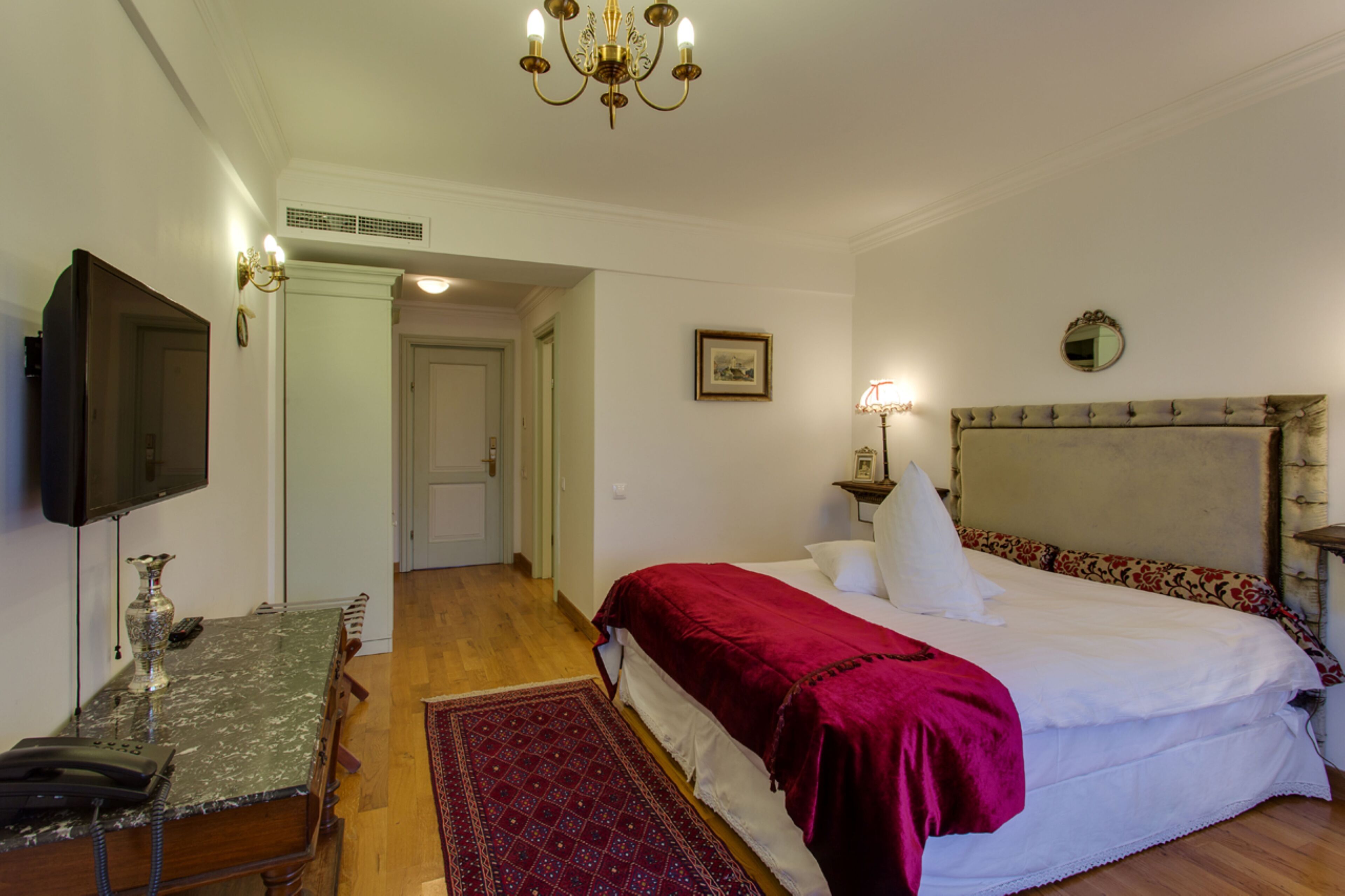 A bedroom with a bed, a television, a desk, and a chair.
