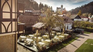 A courtyard with outdoor seating, a stone wall, and a view of a castle in the background.