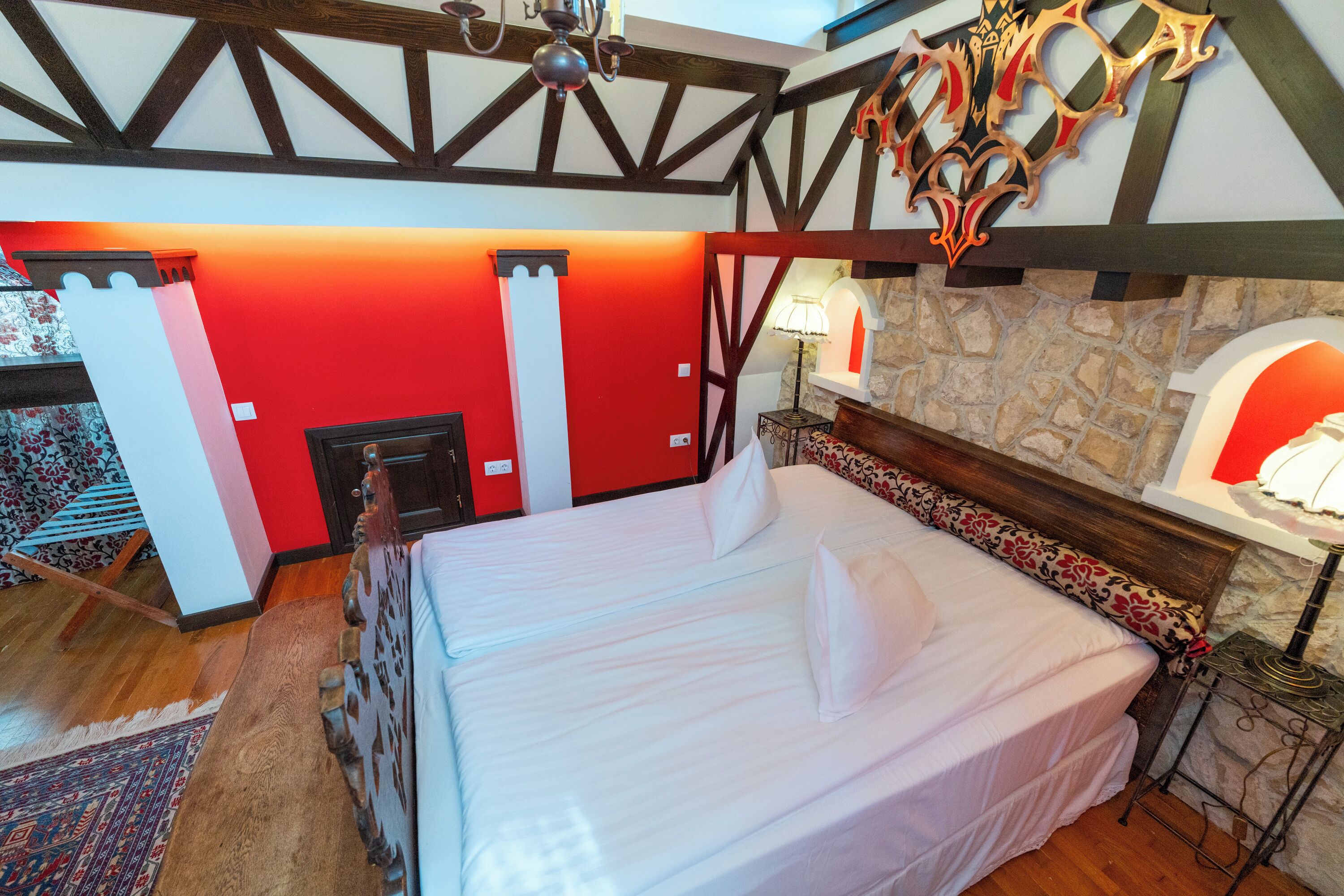 Un dormitorio con una cama grande, una chimenea de piedra y una pared de acento roja.