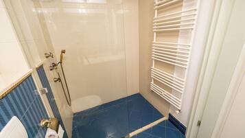 A bathroom with a shower, toilet, and towel rack.