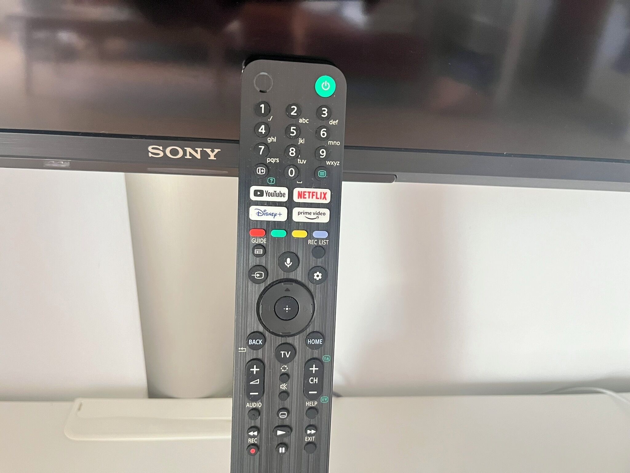 A Sony remote control with a numeric keypad, directional pad, and various function buttons including YouTube, Netflix, and Guide.