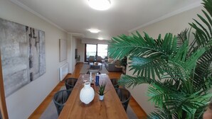 Un'ampia sala da pranzo con un tavolo in legno, sedie e un'ampia pianta in vaso.