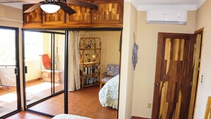 A bedroom with a bed, a ceiling fan, a wooden wardrobe, a bookshelf, and a sliding glass door leading to a balcony. - A-404 Enjoy Your Vacation In This Beautiful Condominium! (Cabo San Lucas)