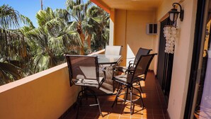 A balcony with a table and chairs, overlooking palm trees. - A-404 Enjoy Your Vacation In This Beautiful Condominium! (Cabo San Lucas)
