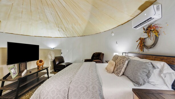 Hotelkamer met een groot bed, een flatscreen-tv, een bureau met lamp en een wandairconditioner.