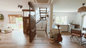A modern interior with a staircase, a dining area, and a kitchen. - Vila Vale Guest House surf e yoga (Almada)