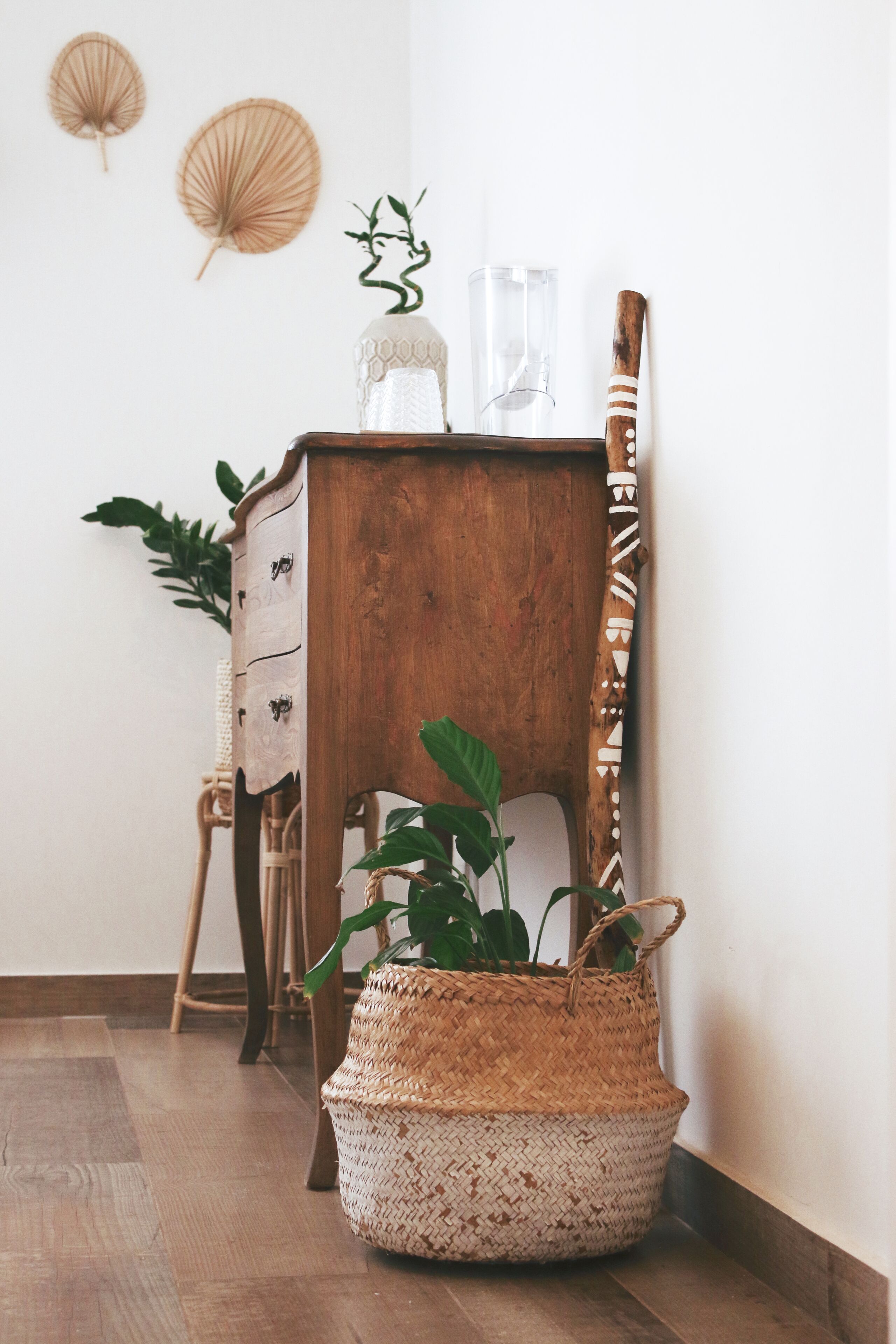 Eine Holzkommode mit Schubladen, ein geflochtener Korb und ein Blumentopf.
