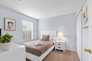 Une chambre à coucher avec un lit, une table de chevet, une lampe et un tableau encadré au mur.
