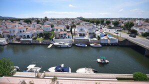 A marina with boats docked, surrounded by white buildings with red-tiled roofs, under a clear sky. - 224-Apartment with view on marina , pool and parking (Empuriabrava)