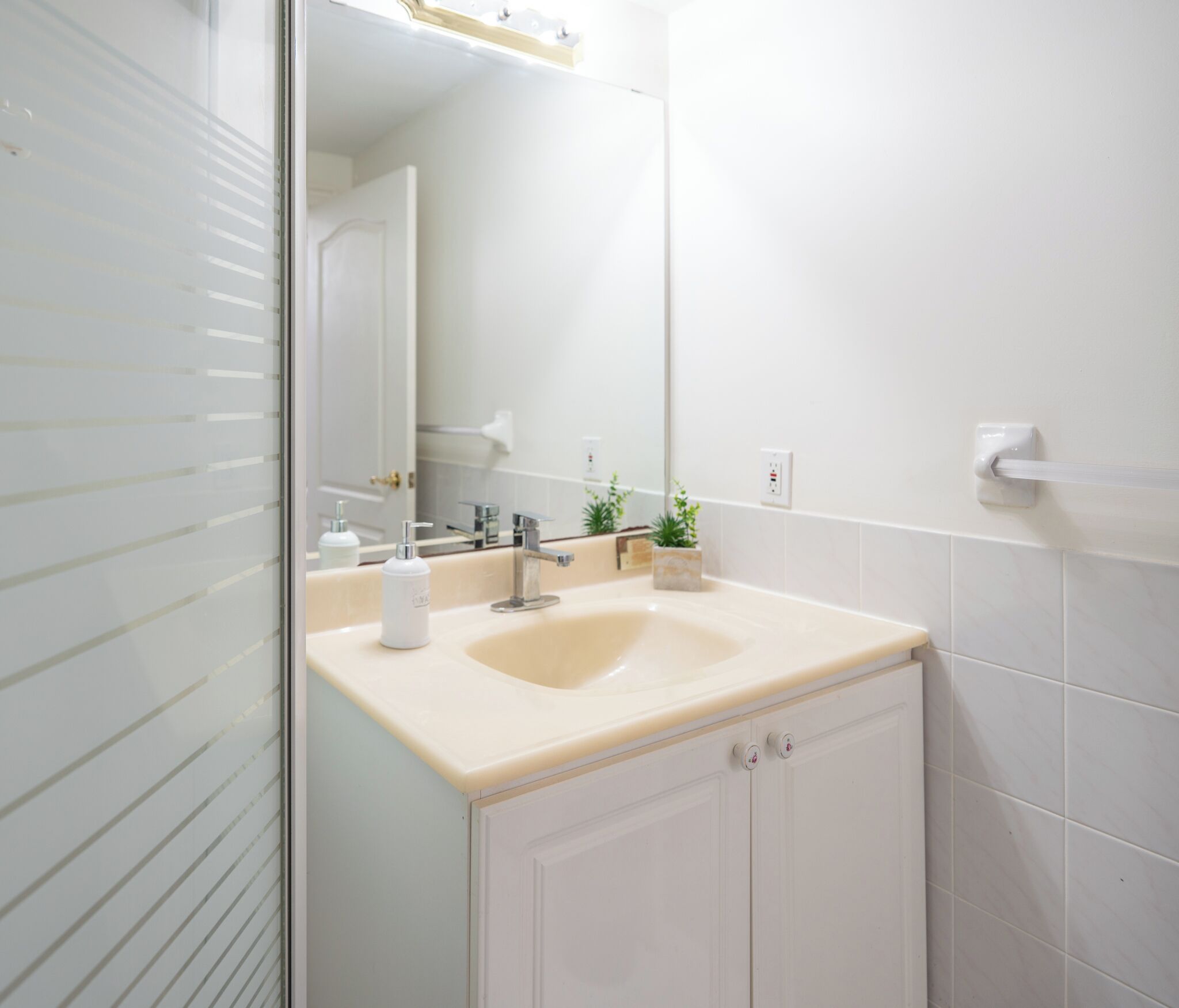 Een badkamer met een witte wastafel, een spiegel en een kastje.