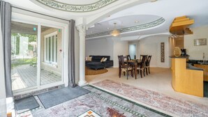 A spacious living area with a sofa, dining table, and chairs, a kitchen area with a wooden counter, and a large glass door leading to an outdoor patio. - 25% Fall OFF, Luxury 3 Bdrms, 2 Baths, 2 Prk (Richmond Hill)