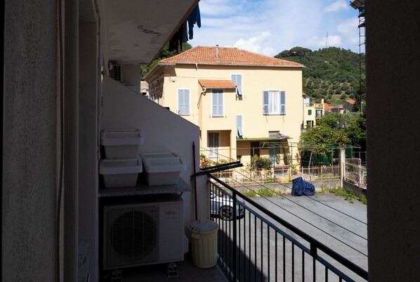A balcony with a Fujitsu air conditioner, a trash bin, and a blue bag on the ground. - Casa Rattazzi by Wonderful Italy (Albisola Superiore)