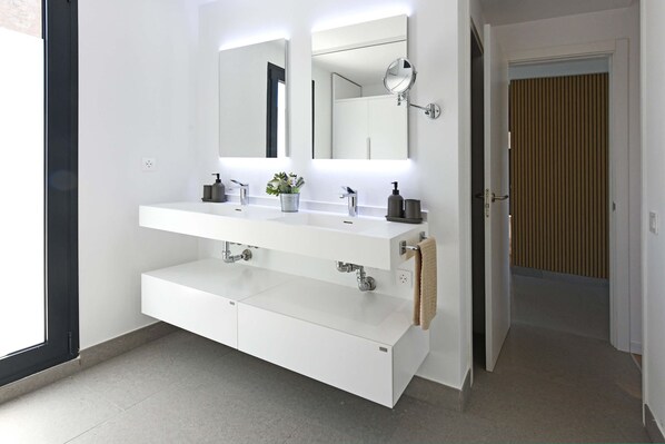 Uma casa de banho moderna com um lavatório branco, espelho e porta-toalhas.