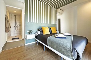 Ein modernes Schlafzimmer mit Bett, Nachttisch und einer Duschkabine.
