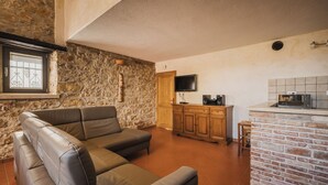Ein Wohnzimmer mit Steinsandsteinwand, einer Holzeinrichtung, einem Fernseher und einer Küchenzeile mit einer Mikrowelle.
