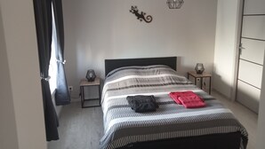 Ein Schlafzimmer mit einem Bett, zwei Nachttischen, einer Pendelleuchte und einem Kleiderschrank.