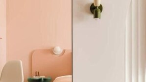 A room with a pink wall, a white bed, a green side table, and a white chair. - Pops Apartment

 (Kraków)