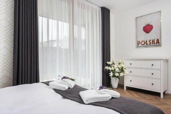 Relax in a serene space with a large bed, white dresser, and potted plant.