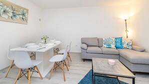 A modern living room with a dining area, grey sofa, and a small table with a pink candle. - Holiday house CHARMING with private pool (Kras)