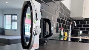 A modern kitchen with a built-in washer and dryer, a stainless steel sink, and a black tiled backsplash. - Cozy and modern studio in prime location-perfect for your getaway (Brighton and Hove)