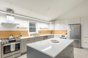 Una cocina moderna con una isla central, electrodomésticos de acero inoxidable y vistas al exterior a través de una ventana.