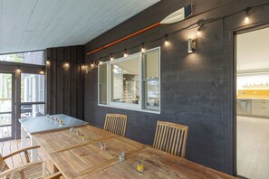 Una mesa de comedor de madera con sillas, un ventanal y luces colgantes.