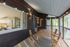 Un comedor con una mesa grande, sillas de madera y luces de cuerda.