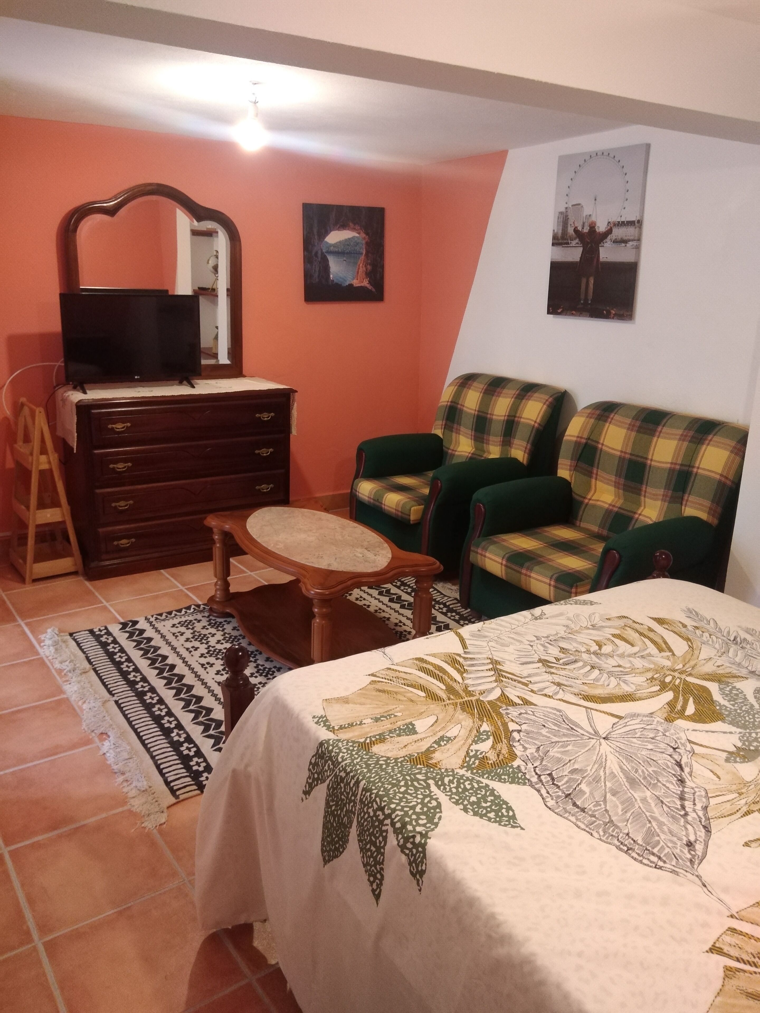 Une pièce comprenant un lit, une commode, une chaise, un miroir et deux tableaux encadrés accrochés au mur.
