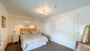 A bedroom with a bed, bedside tables, a wardrobe, a mirror, and a ceiling light fixture.