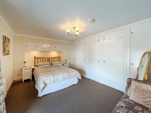 A bedroom with a bed, bedside tables, a wardrobe, a mirror, and a ceiling light fixture.