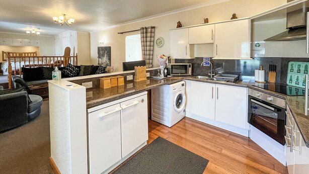 A modern kitchen with white cabinetry, a built-in microwave, and a stainless steel range hood.