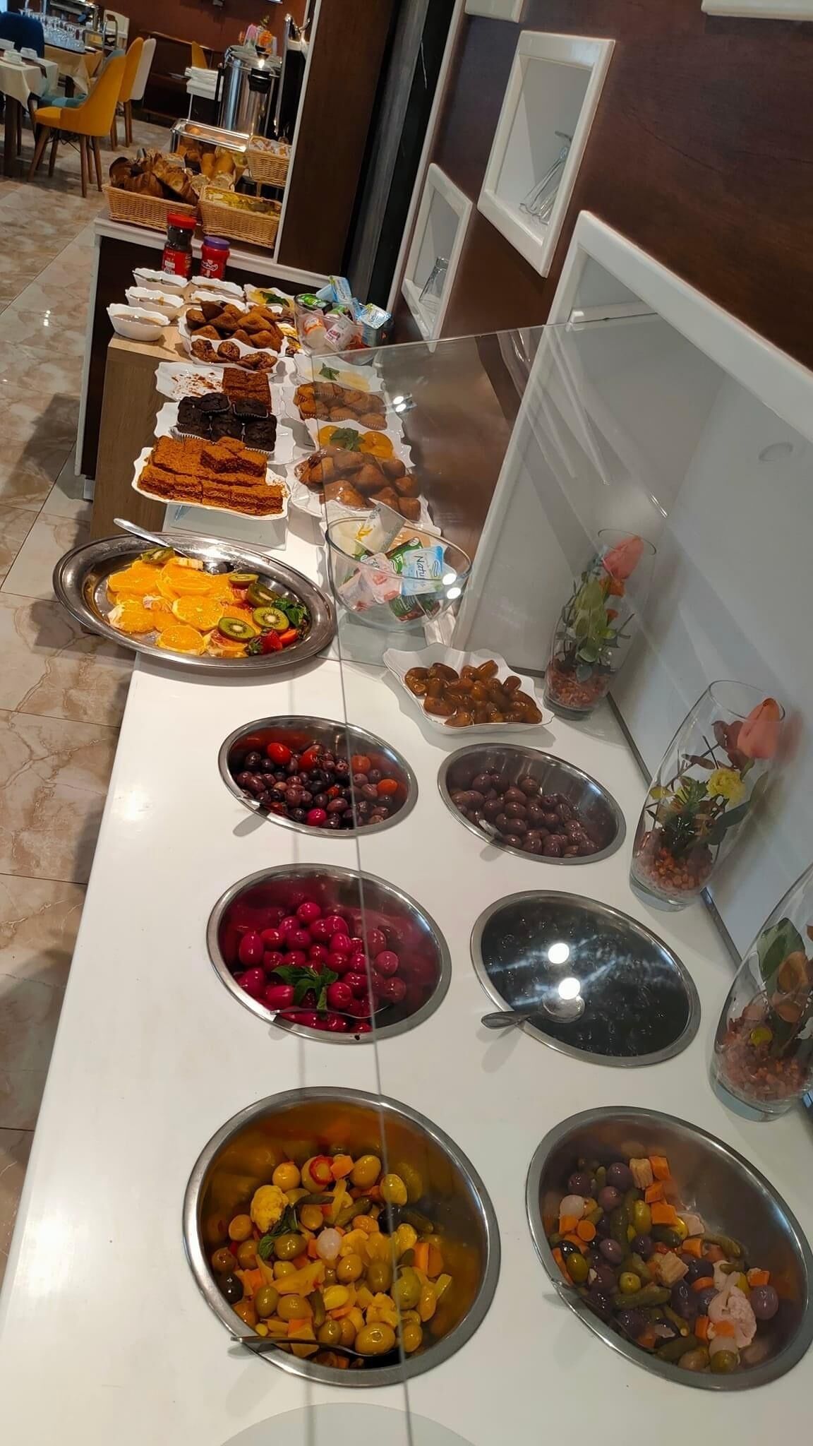 A buffet with various food items including fruits, vegetables, and desserts.