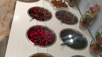 A buffet with various food items including fruits, vegetables, and desserts.