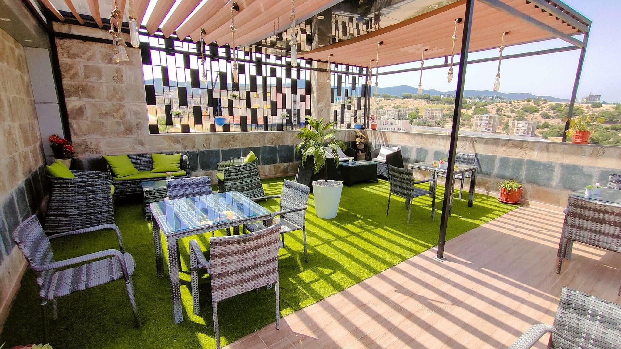 A rooftop patio with outdoor furniture, a grill, and a view of the cityscape.