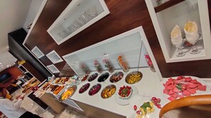 A buffet with various food items and a wine display. - Hotel Boulefkhad (Filfila)